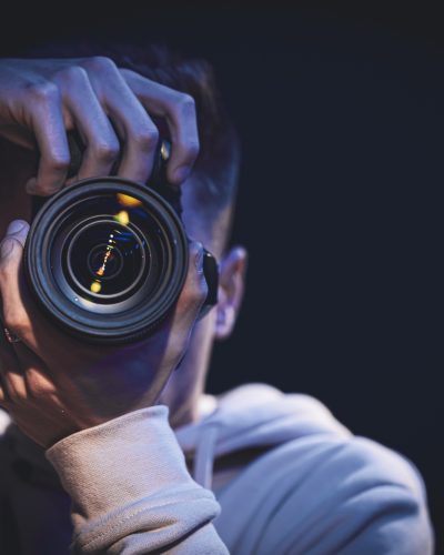 A man photographer with a camera takes a photo in the dark, copy space.